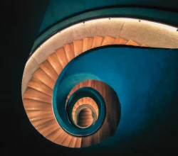 Curved spiral staircase with blue and wooden steps viewed from the top
