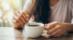 Close-up of person stirring coffee alone at a table representing how routine can distance people in a relationship
