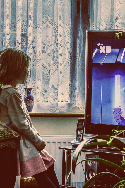 Child sitting indoors watching television screen representing our early conditioning