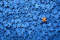 Blue jigsaw puzzle pieces with one contrasting orange piece not fitting