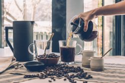 Person pouring coffee into a glass mug on a table, representing daily life in a couple