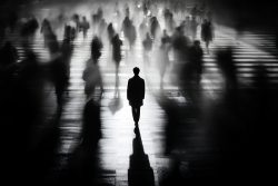 Person standing still in a blurred crowd crossing a street