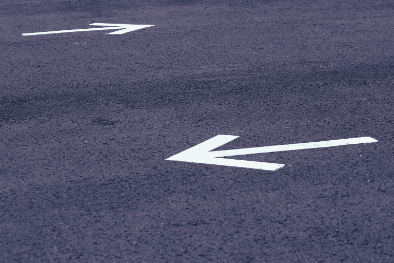road surface with white arrows pointing in opposite directions