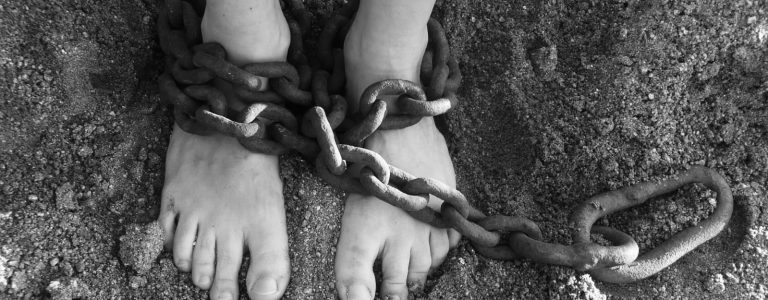Person’s feet chained together with metal shackles